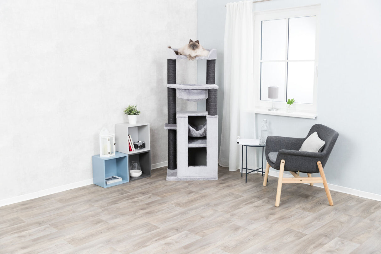 Hellgrauer Kratzbaum mit schwarzem Standbein, darauf liegende Katze im modernen Wohnzimmer mit Stuhl.