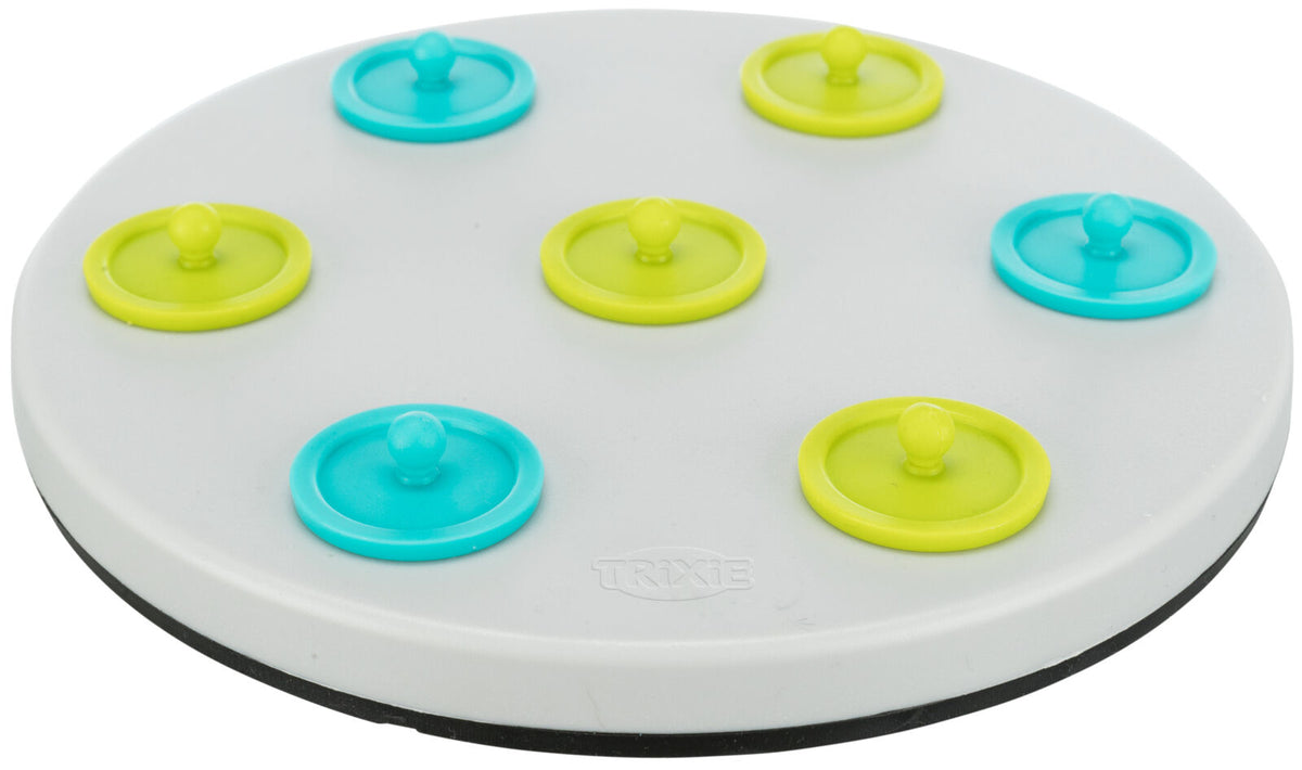 Rundes weißes Spielzeug mit sieben abnehmbaren Deckeln in Blau und Gelb, Marke "Trixie" sichtbar.
