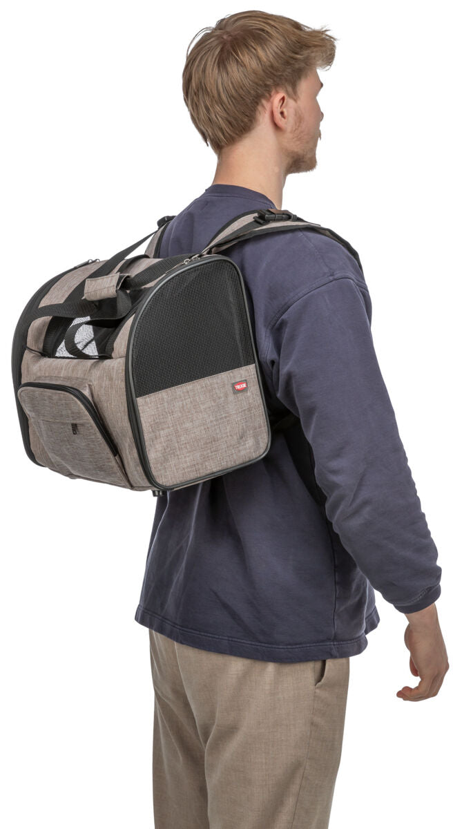 Eine Person trägt einen beige-braunen Rucksack mit schwarzen Netzpanelen auf dem Rücken, seitlich betrachtet.