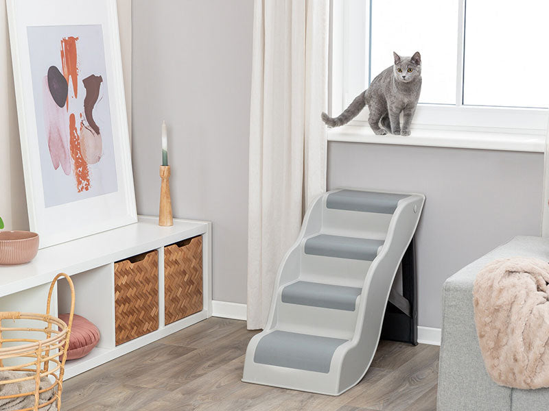 Katze sitzt auf Fensterbank über einer grauen Haustiertreppe mit rutschfesten Stufen in modern eingerichteter Wohnung.