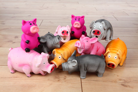 Mehrfarbige Spielzeugschweine stehen auf einem Holzboden in einer Gruppe zusammen.