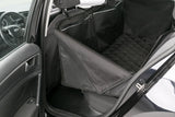 Eine schwarz gepolsterte Auto-Rücksitzabdeckung aus Stoff, sichtbar vom geöffneten Fahrzeugheck.