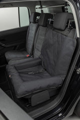 Eine schwarze Hundesitzdecke ist auf dem Rücksitz eines Autos befestigt.