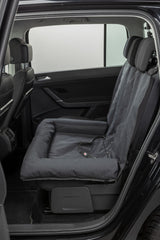 Schwarzer Autositzbezug mit gepolstertem Hundeplatz in der Rückbank eines Autos.