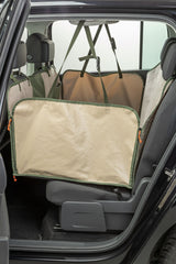 Schützende Rücksitzabdeckung in beige und grün, befestigt im Inneren eines Autos.