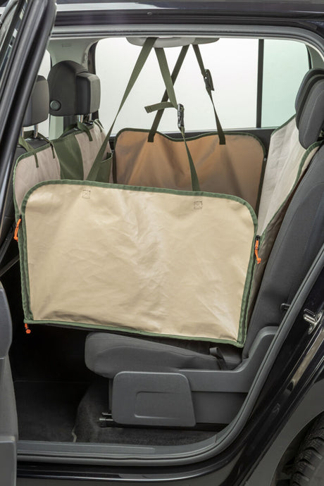 Schützende Rücksitzabdeckung in beige und grün, befestigt im Inneren eines Autos.