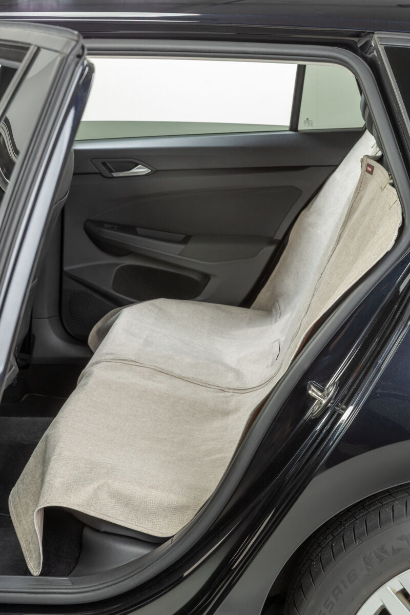 Beige Sitzschoner bedeckt Rücksitz eines geöffneten Autos.