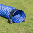 Blauer Tunnel aus Stoff auf grünem Gras liegend, mit schwarzem Rand am Eingang, Tunnel für Outdoor-Aktivitäten.