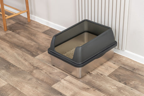 Offene Katzentoilette mit schwarzem Rand steht auf einem Holzfußboden.