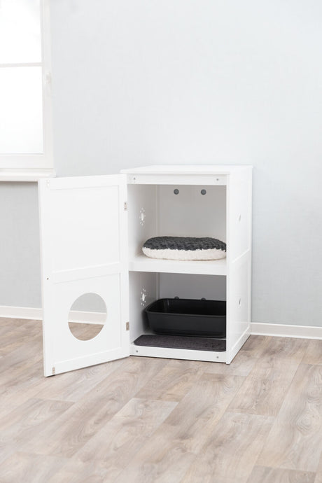 Ein weißes Schrankmöbel mit offener Tür zeigt eine schwarze Katzentoilette unten und ein rundes Kissen oben.