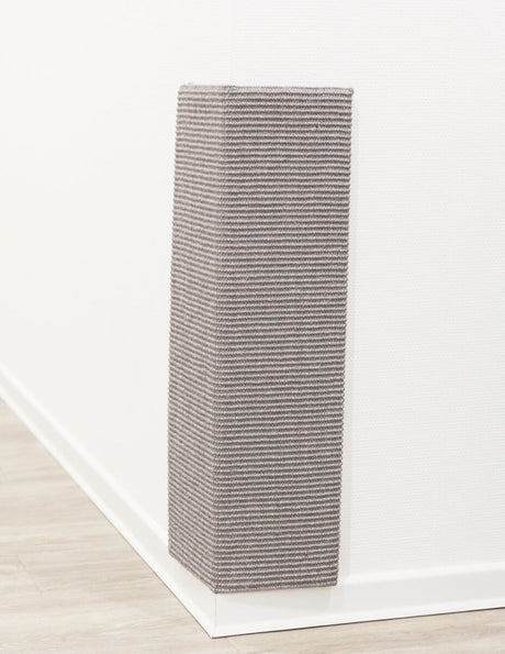 Eckige Wandverkleidung aus grauem, geripptem Material, montiert an einer weißen Wand mit Holzfußboden.