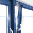 Ein gekipptes blaues Fenster mit einem weißen Gitter, das in den Spalt eingesetzt ist.