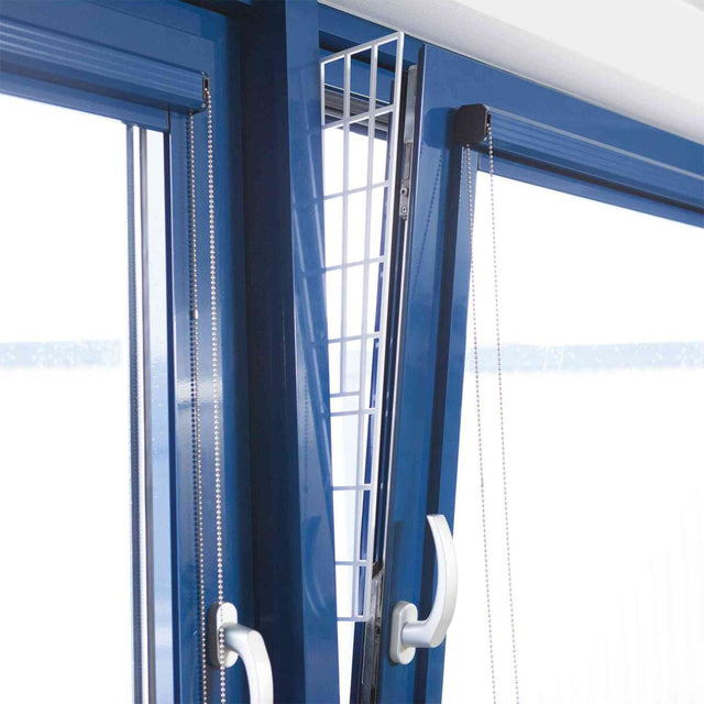Ein gekipptes blaues Fenster mit einem weißen Gitter, das in den Spalt eingesetzt ist.