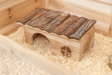 Holzhaus mit Rindendach in einem mit Sägespänen bedeckten Käfig, hat zwei Öffnungen und eine kleine Fensterform.