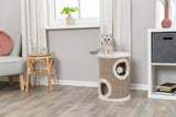 Eine graue Katze sitzt auf einem beige-weißen Kratzbaum in einem hellen Wohnzimmer mit Holzboden.
