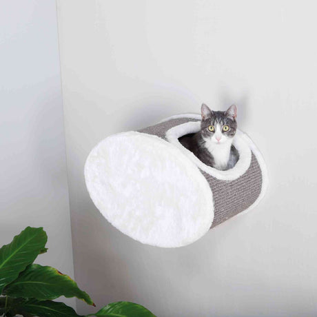 Graue und weiße zylindrische Höhle zeigt eine Katze, die aus der Öffnung herausschaut, mit einer Pflanze im Vordergrund.