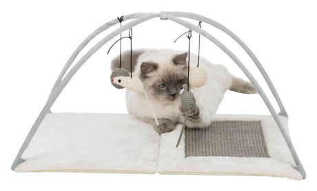 Katze spielt unter einem hellgrauen Spielbogen mit hängenden Spielzeugen auf einer weißen, weichen Unterlage.