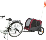 Ein Fahrradanhänger in Rot und Schwarz mit Netzeinsätzen und einer orangenen Sicherheitsflagge, die an einem weißen Fahrrad befestigt ist.