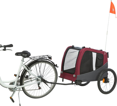 Fahrrad mit hinten befestigtem rot-schwarzen Fahrradanhänger, der ein Netzfenster und eine orangefarbene Fahne hat.