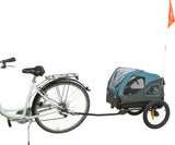 Ein Fahrrad mit angekoppeltem blauen Fahrradanhänger und orangefarbener Fahne auf grünem Hintergrund.