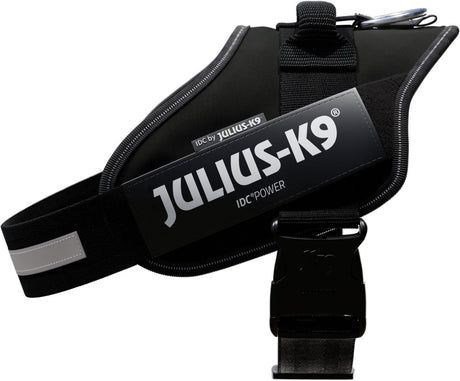Hundegeschirr in Schwarz mit grauem Logo "Julius-K9 IDC" auf der Seite, reflektierender Streifen sichtbar.