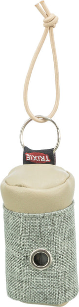Beigefarbener Tasche mit Kordel, Metallring und kleiner Öffnung auf der Vorderseite, Text "TRIXIE" sichtbar.