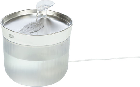 Runder, transparenter Wasserspender mit silbernem Deckel und leichtem Wasserfluss, weißes Kabel sichtbar.