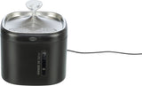 Schwarzer Trinkbrunnen mit Edelstahl-Oberfläche, Wasserstrahl, sichtbare Max- und Min-Markierung, Kabel.