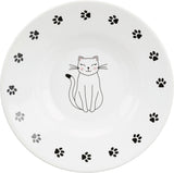 Weiße Schüssel mit Katzendesign in der Mitte und schwarzen Pfotenabdrücken am Rand.