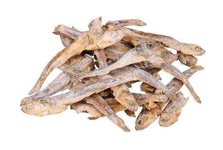 Ein Stapel kleiner getrockneter Fische auf weißem Hintergrund, die braun und beige gefärbt sind.