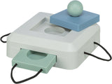 Quadratische weiße Box mit blauen und grünen Elementen, runder Ball oben, zwei herausziehbare, gelochte Platten an den Seiten.