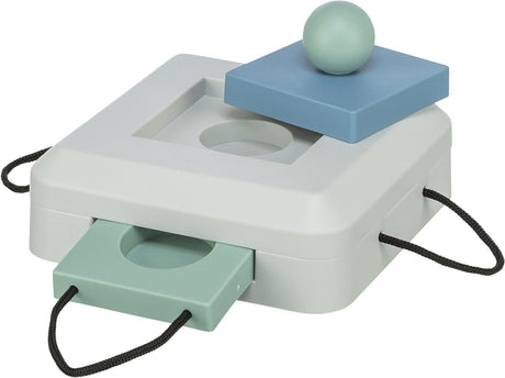 Quadratische weiße Box mit blauen und grünen Elementen, runder Ball oben, zwei herausziehbare, gelochte Platten an den Seiten.