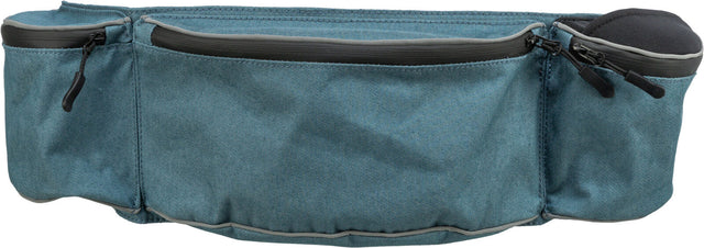 Blau-grüne Tasche mit mehreren Reißverschlüssen, aus Stoff mit sichtbarer Naht, zwei abgerundete Seitentaschen.