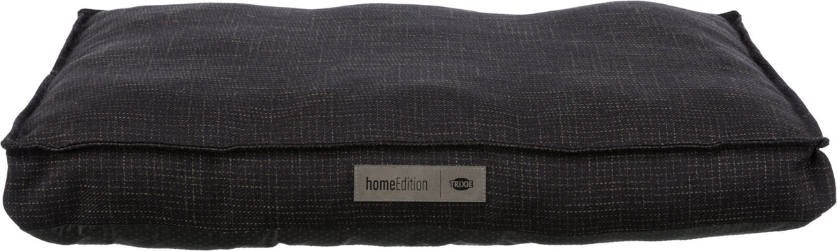 Rechteckiges, dunkles Kissen mit feinem Muster und einem Etikett mit der Aufschrift "homeEdition Trixie".
