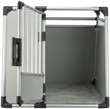 Silberner Transportkäfig aus Metall mit offener Tür, schwarzem Griff und grauem Boden innen.