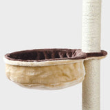Beiges, rundes Tierbett aus Plüsch, das an einem Kratzbaum befestigt ist, mit dunkelbraunem Rand.