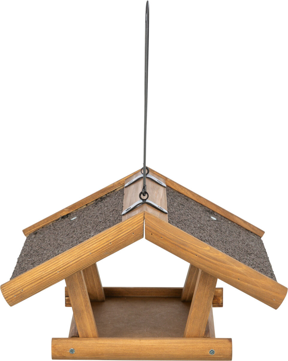 Holzfarbenes Vogelhaus mit schrägem Dach und dunklem Dachbelag, mit mittiger Aufhängevorrichtung.