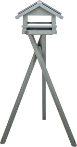 Graues Vogelhaus in dreieckiger Form auf einem hohen, dreibeinigen Ständer aus Holz.