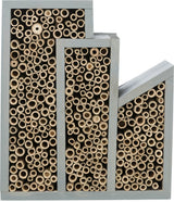 Rechteckiges Insektenhotel aus Holz mit unterschiedlich dicken, natürlichen Bambusröhren in mehreren Fächern.