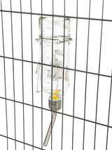 Transparente Wasserflasche mit Skala auf einem Metallgitter befestigt, mit Trinkröhrchen und gelbem Element innen.