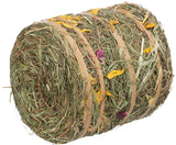 Zylinderförmiges Bündel aus getrocknetem Gras und Blumen mit gelben und violetten Blütenelementen, gebunden mit Bändern.