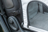 Nahaufnahme eines weißen Transportrucksacks mit schwarzem Netz und Reißverschlüssen im Auto.