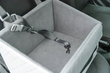 Grauer Transportsitz mit Sicherheitsgurt befindet sich in einem Fahrzeug.