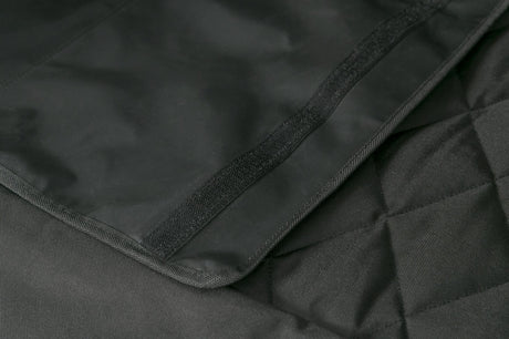 Schwarzes gewebtes Material mit diagonal verlaufender Naht und Klettverschluss auf einer Oberfläche.