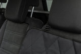 Schwarzer, gesteppt aussehender Schonbezug auf einem Rücksitz im Auto.