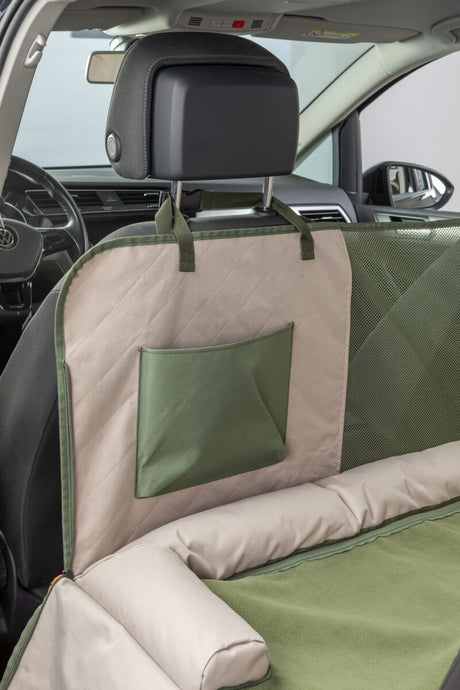 Beige-grüne Autodecke mit Tasche schützt die Rückbank eines Autos.