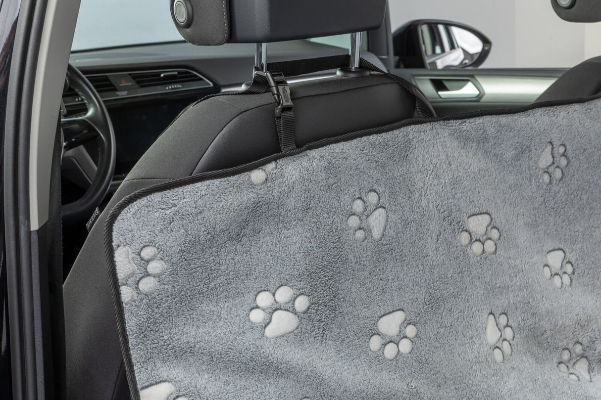 Graue Autositzabdeckung mit Pfotenmustern hängt über der Rückbank im Innenraum eines Autos.