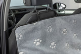 Graue Autositzabdeckung mit Pfotenmustern hängt über der Rückbank im Innenraum eines Autos.