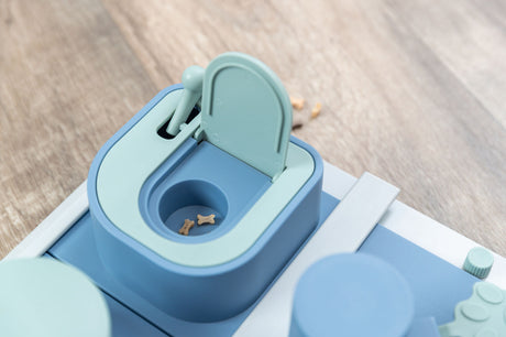 Interaktives Hundespielzeug aus blauem und mintgrünem Plastik auf Holzfußboden.