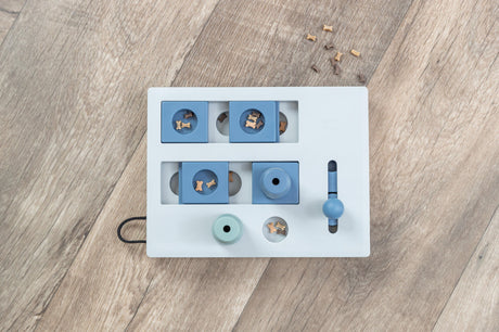 Puzzle-Spielzeug für Hunde mit blauen und weißen Elementen liegt auf Holzboden.